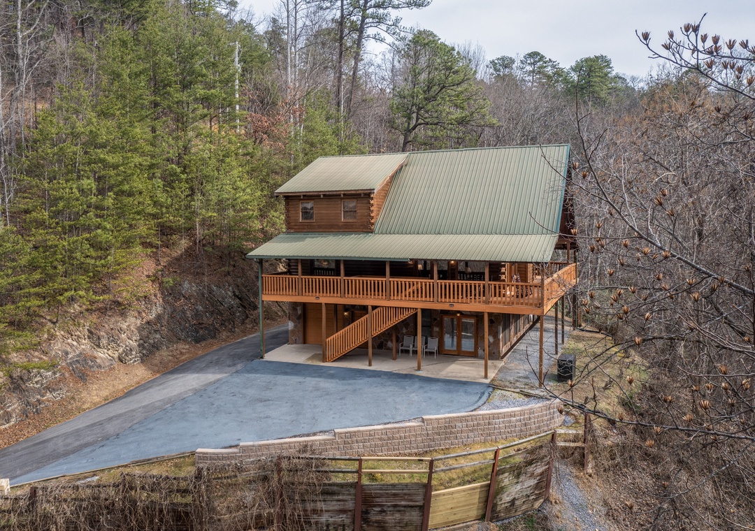 A rustic log cabin nestled among towering trees, featuring a spacious deck and private parking for your mountain getaway.