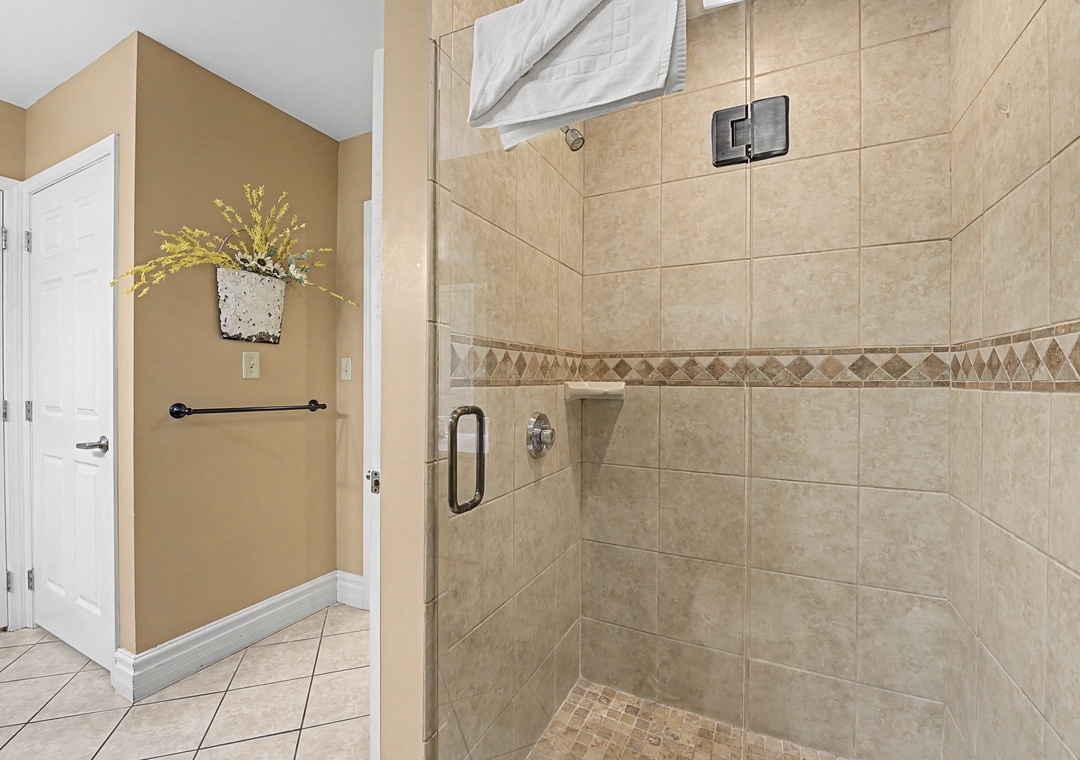 Step into your spacious glass-enclosed shower with elegant tile work and premium fixtures for a refreshing start to your day.