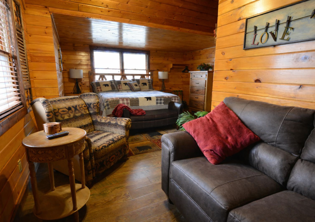 Your cozy cabin bedroom combines rustic charm with modern comfort, featuring warm wood walls and plush seating for relaxing after your adventures.