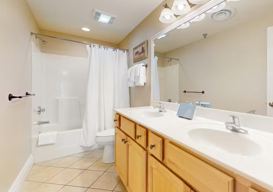 Your spacious bathroom features a luxurious bathtub-shower combo, double vanity sinks, and warm wood cabinetry for all your essentials.