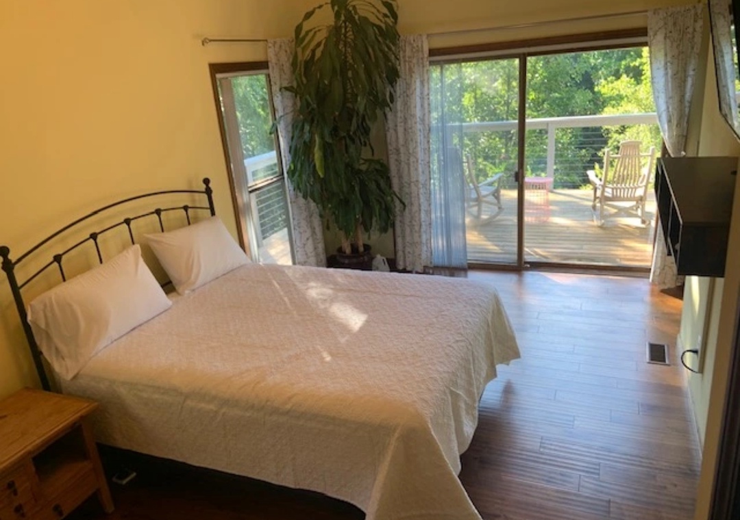 Step into your serene bedroom where crisp linens await and sliding doors reveal your private deck overlooking lush greenery.