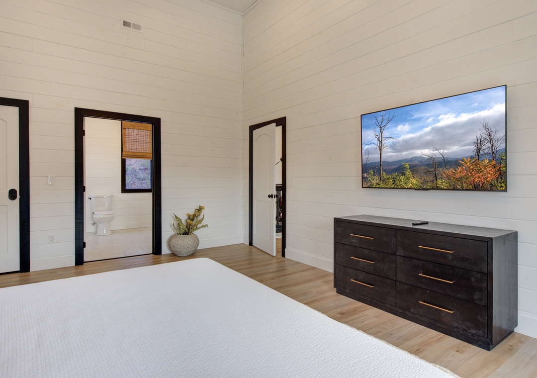 Your spacious bedroom features elegant white shiplap walls, warm wood floors, and a wall-mounted TV for cozy evenings in.