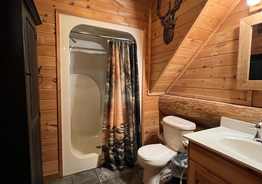 Step into your rustic cabin bathroom, where warm wood paneling and charming decor create a cozy mountain retreat. Everything you need—shower, vanity, and woodland-inspired touches—awaits your arrival.