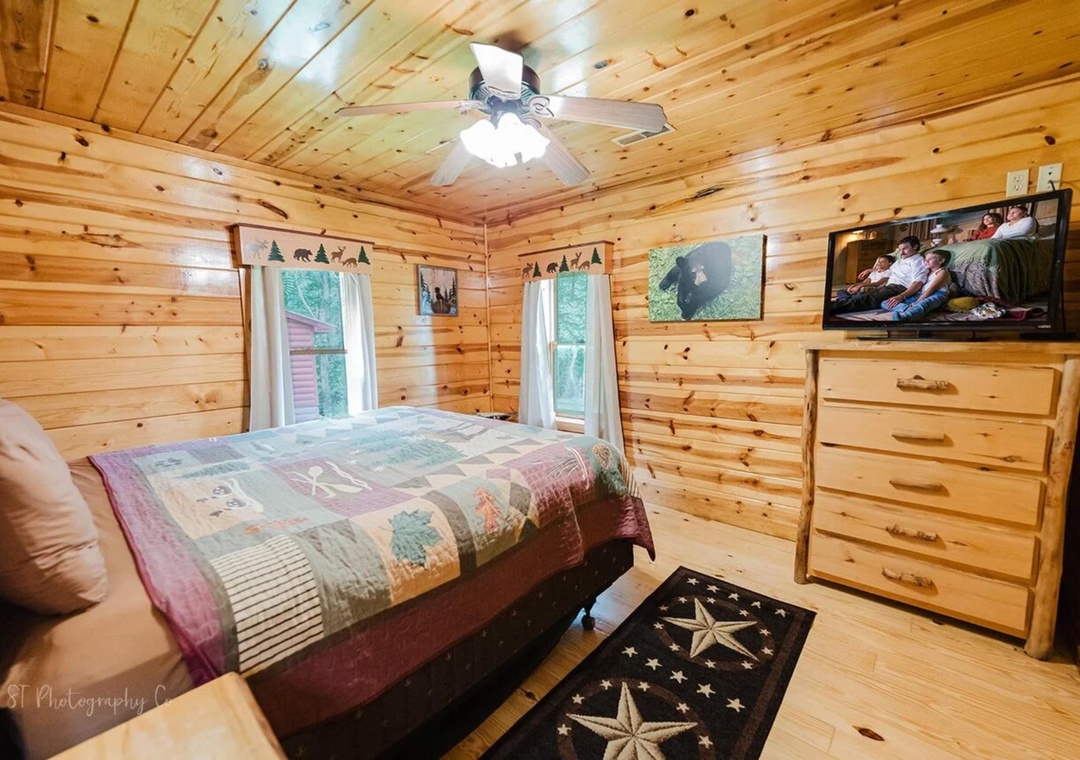 Sink into the cozy bed surrounded by warm pine walls, while your favorite show plays on the TV. The natural light from the windows and rustic charm create your perfect retreat.