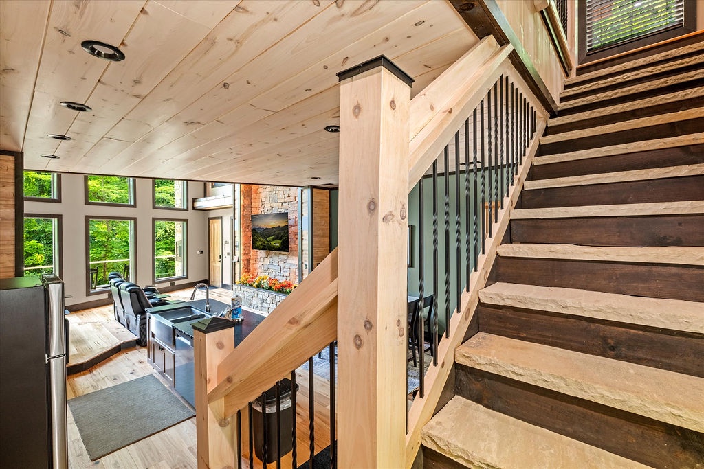 High ceilings and soaring windows frame your retreat where rustic wood meets modern design, centered around a stunning stone fireplace with lush forest views inviting you to unwind.