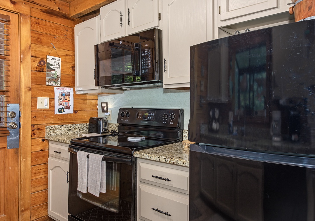Your cabin kitchen comes ready with everything you need—stove, microwave, and a full-size fridge framed by warm wood walls that bring the mountain vibe indoors.