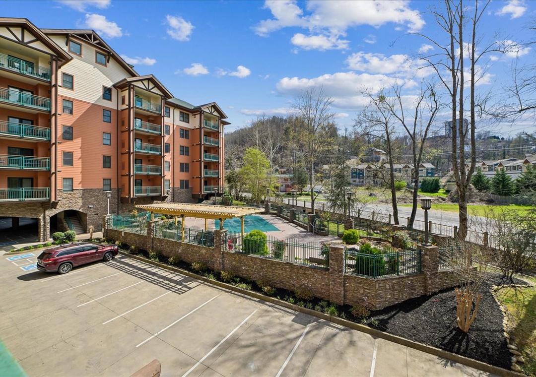 Modern mountain resort complex featuring multi-story buildings, outdoor pool, and convenient parking in a scenic natural setting.