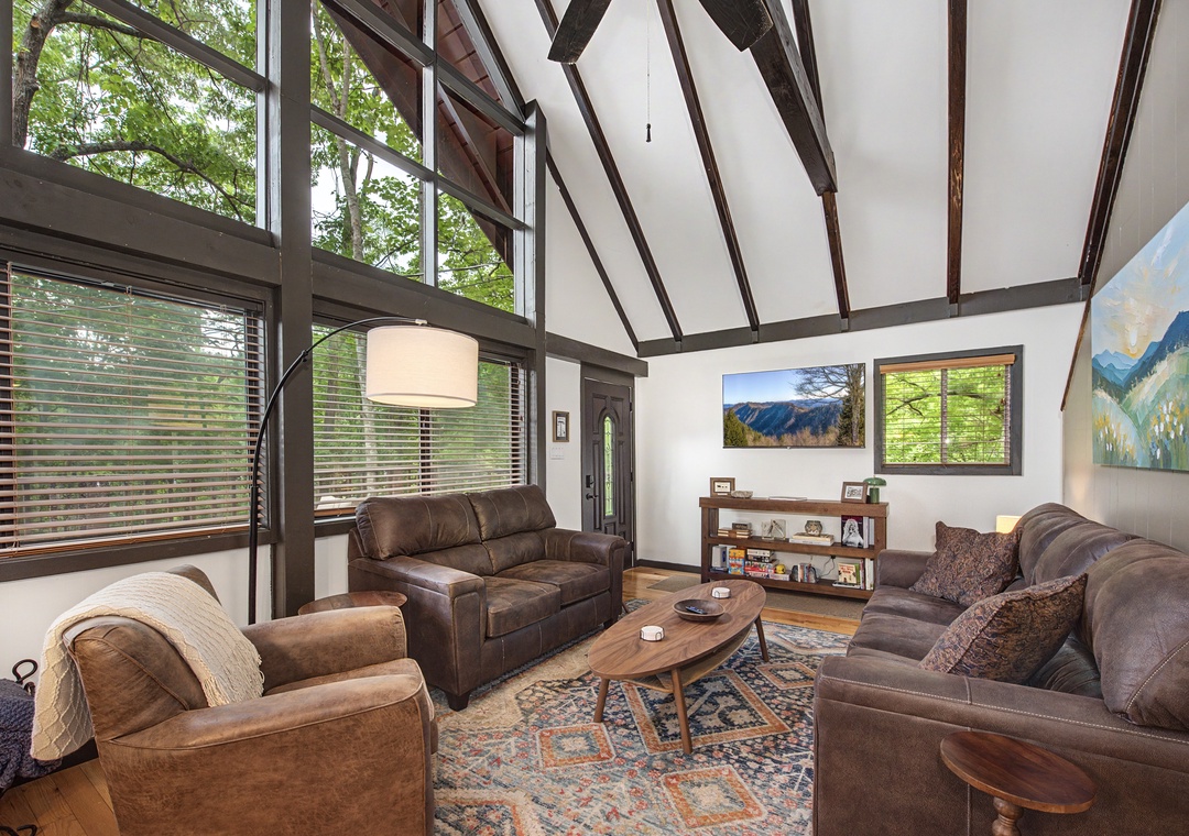 Sink into plush leather sofas beneath soaring vaulted ceilings where natural light pours through towering windows, framing mountain views that bring the outdoors in.