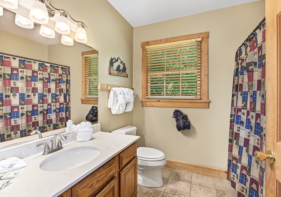 Freshen up in your well-appointed bathroom featuring warm natural wood accents, crisp white linens, and charming mountain-themed décor that sets a cozy, welcoming tone.
