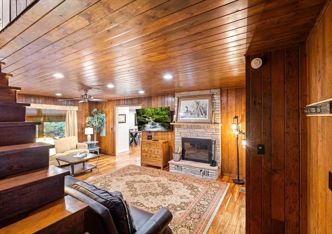 Relax in your warm, wood-paneled living room with rich hardwood floors, a cozy brick fireplace, and comfortable seating that invites you to unwind after a day of adventure.