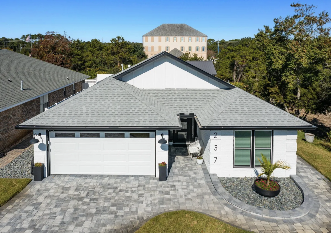 Sandy VaCay, a crisp white exterior brick home with a spacious front yard and parking parking area.