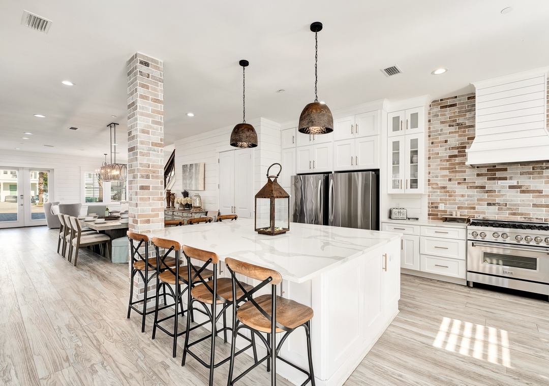 Gather around the bright kitchen island, where crisp white cabinetry meets warm brick accents and modern stainless appliances—your perfect spot for morning coffee or evening conversations.