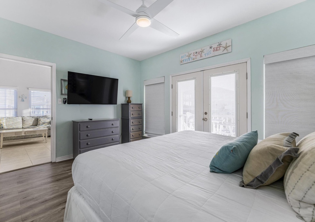 Primary bedroom with large TV and balcony access