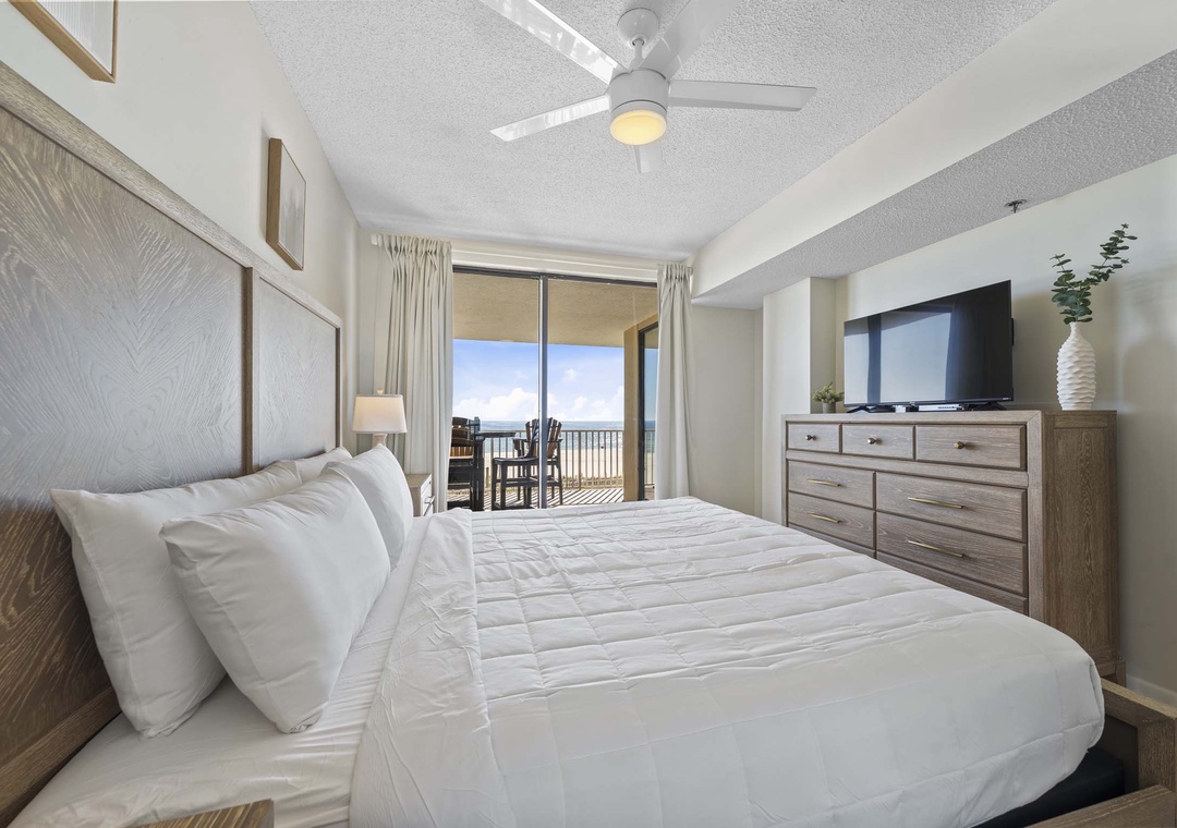 Primary bedroom with flat-screen TV and balcony access