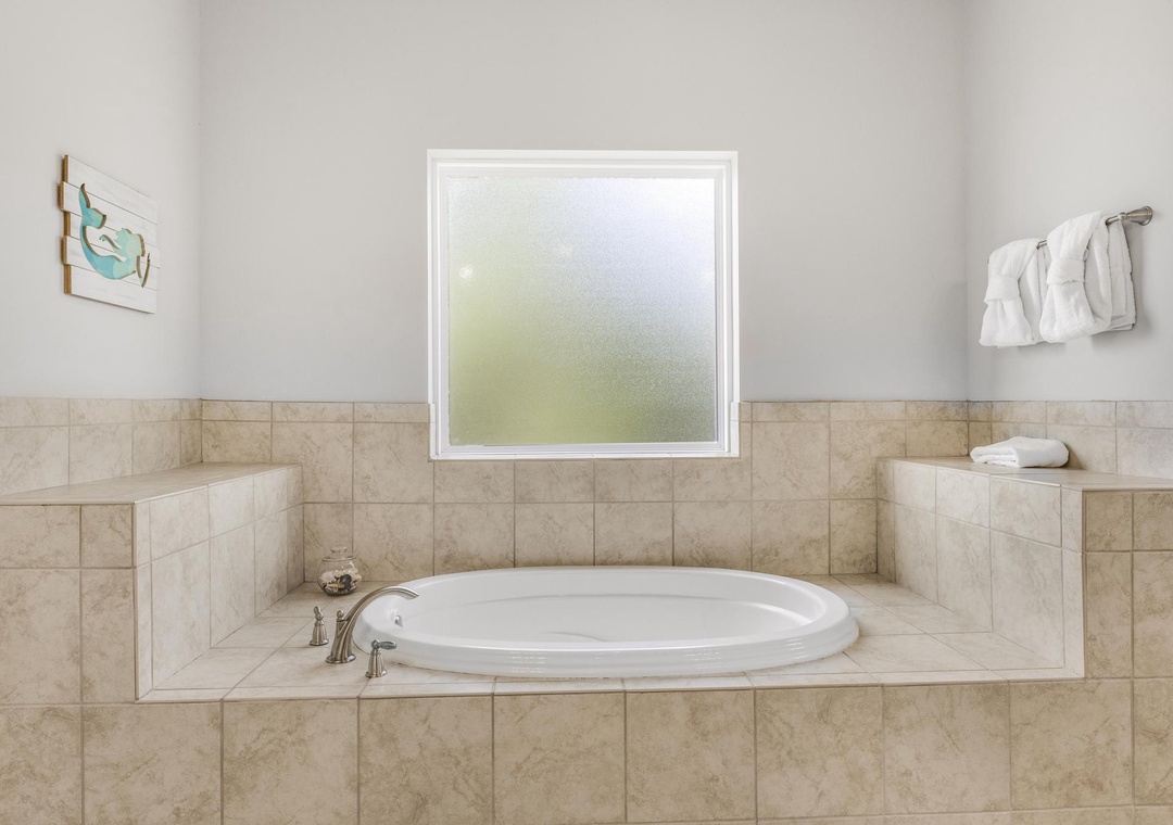 Wind down after a day at the beach in the primary suite bathtub