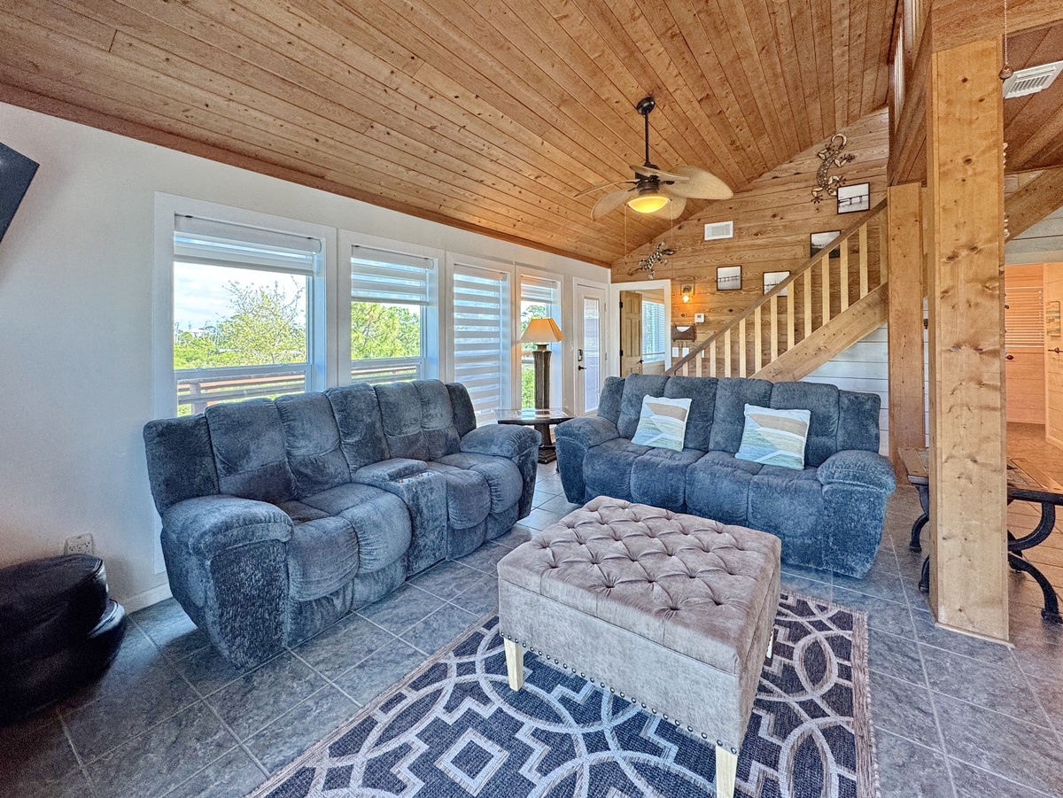 Sink into plush recliners beneath soaring wood ceilings where rustic charm meets modern comfort in your spacious retreat.
