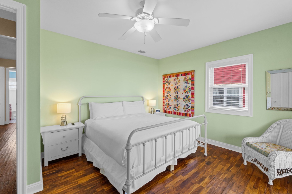 Drift off beneath the gentle breeze of your ceiling fan, wrapped in crisp linens on this inviting bed, with cheerful mint-green walls creating a soothing, restful retreat just for you.