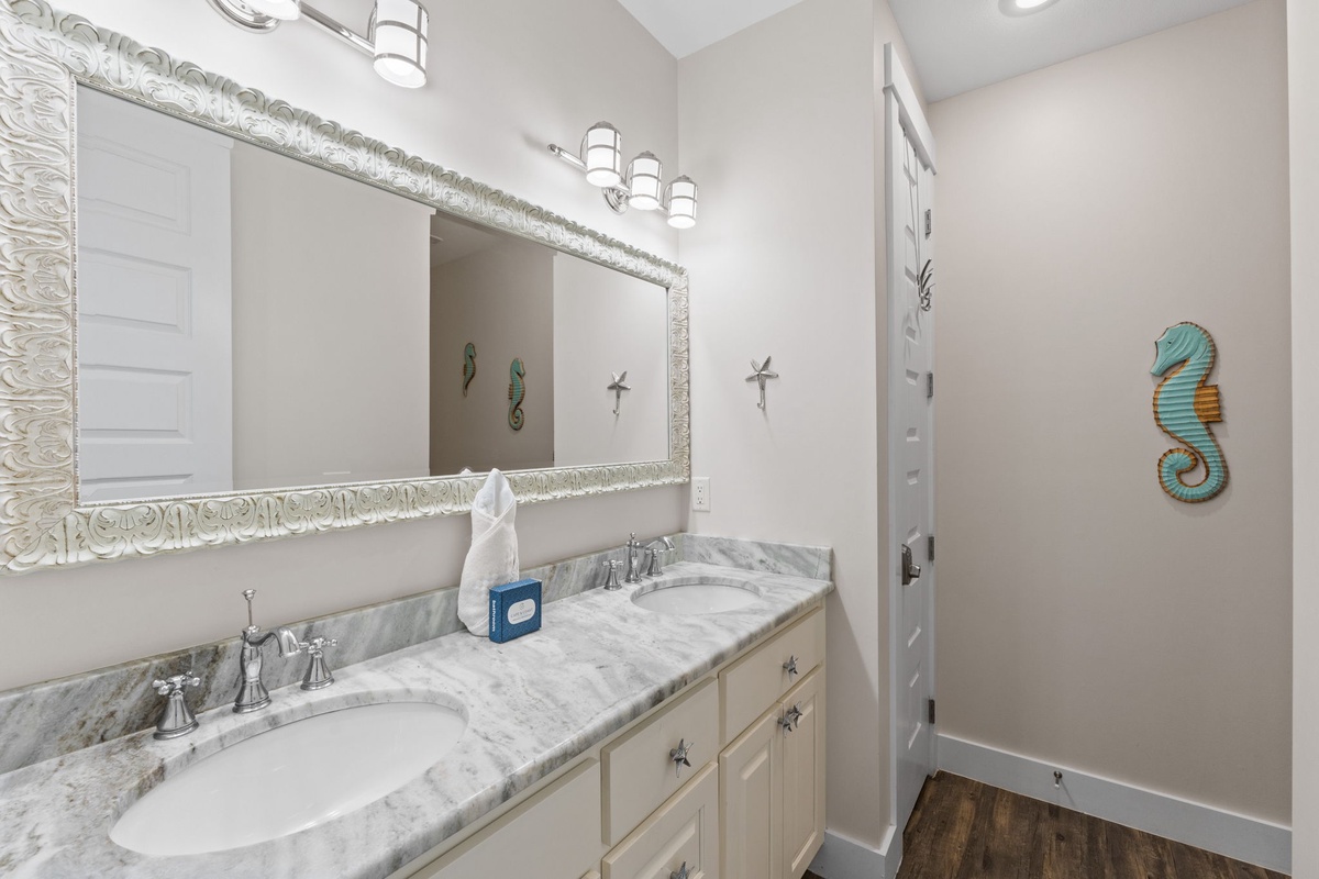 Pamper yourself in this elegant dual-sink bathroom with marble countertops and coastal charm, perfect for your morning routine.