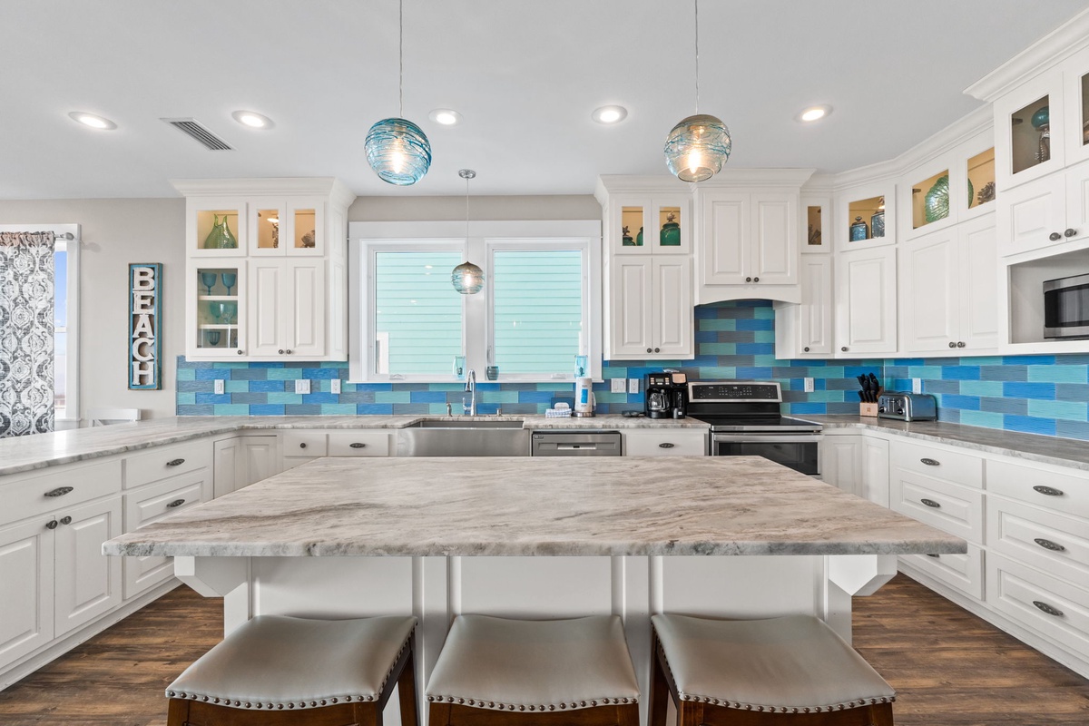 Your bright coastal kitchen awaits with ocean-inspired blue tiles, granite counters, and a spacious island perfect for gathering.