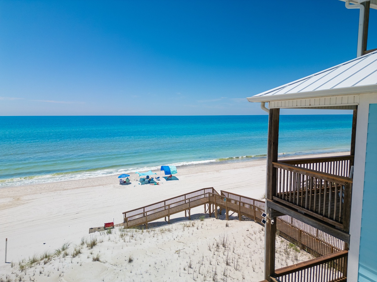A beachside property on Florida's Gulf Coast offers direct access to pristine white sand and turquoise waters under clear blue skies.