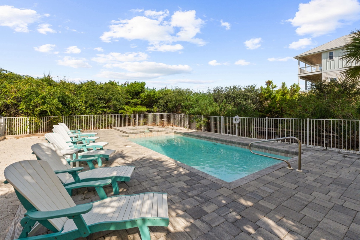 Your private poolside retreat awaits with cheerful lounge chairs and a sparkling pool surrounded by lush greenery, perfect for sunny days of pure relaxation.
