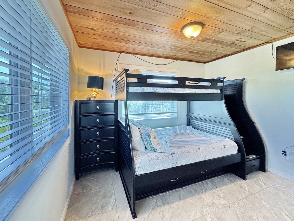 Unwind in your cozy bedroom featuring a stylish bunk bed perfect for families, with warm wood ceilings creating a cabin-like retreat.