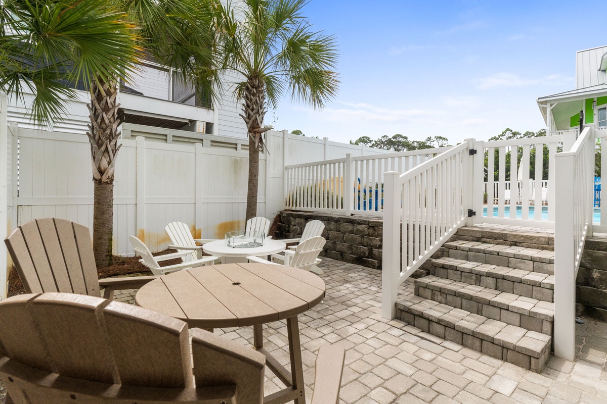 Private courtyard with palm trees, Adirondack chairs, and brick steps leading to the pool—perfect for morning coffee or sunset cocktails.