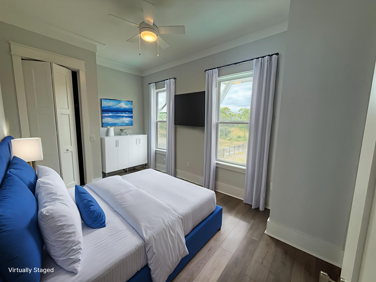 Your peaceful bedroom features crisp white linens with blue accents, a gentle ceiling fan, and natural light streaming through your private windows.