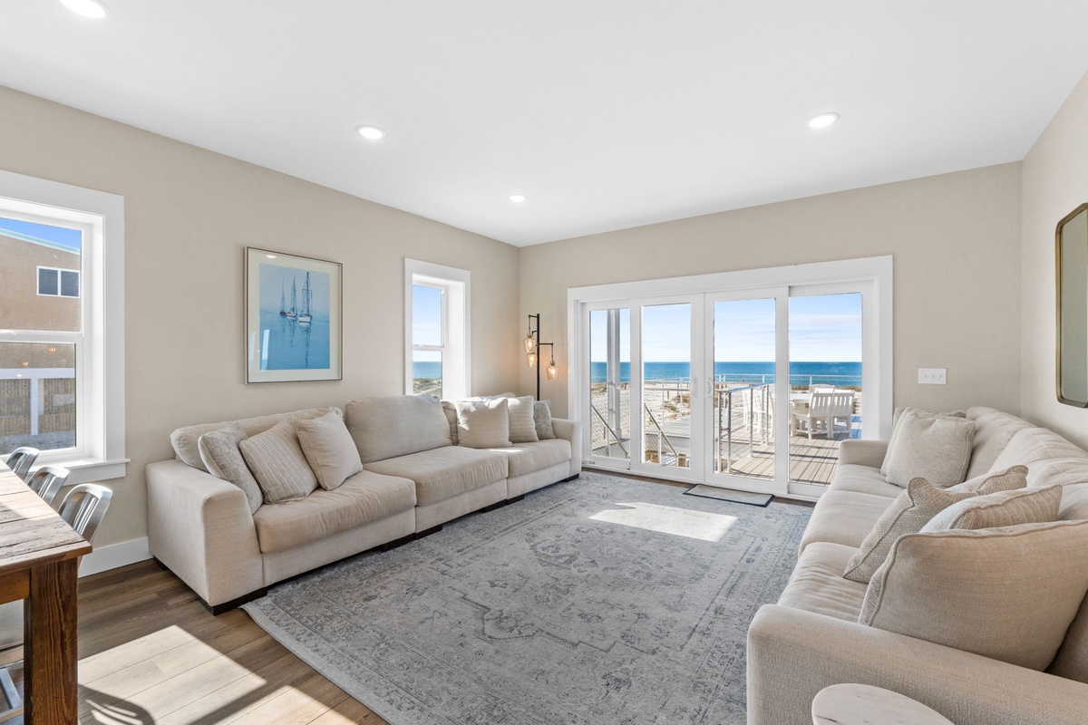Relax in your bright living room with plush seating and stunning ocean views through floor-to-ceiling windows.