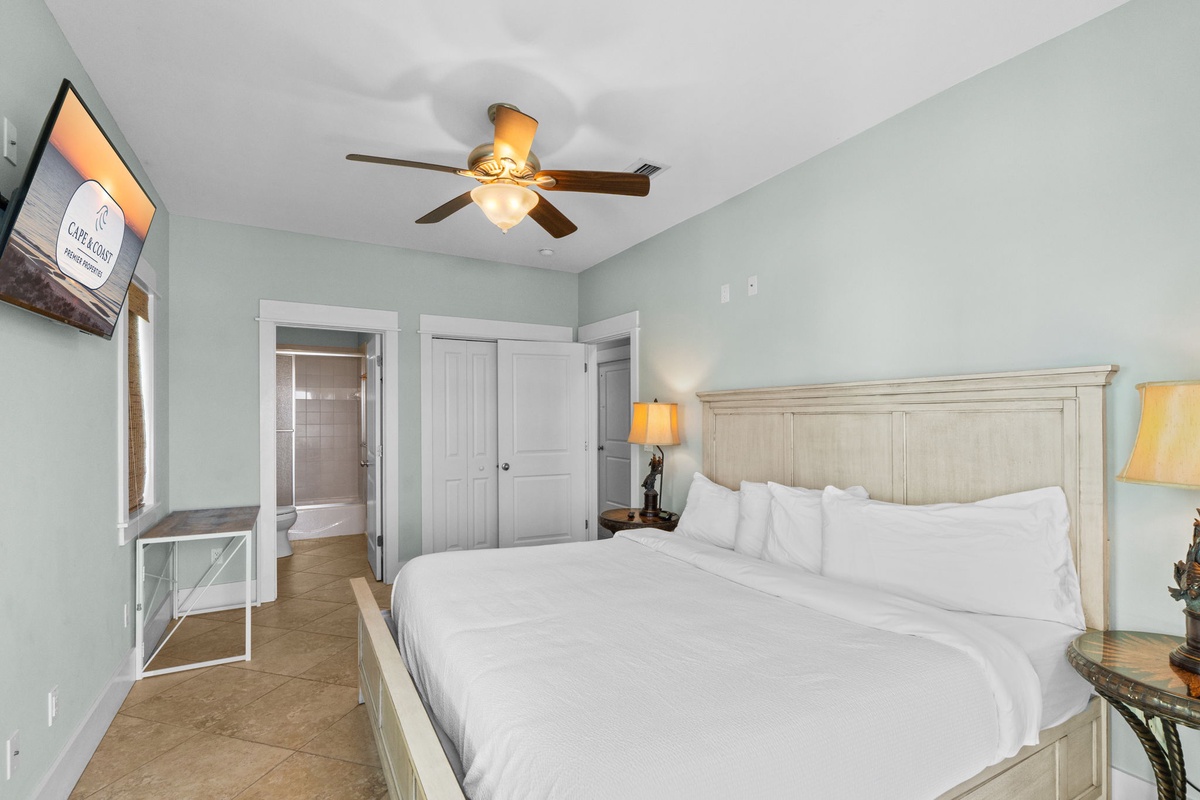 Relax in your serene bedroom with soft mint walls, crisp white linens, and gentle ceiling fan keeping you cool and comfortable.