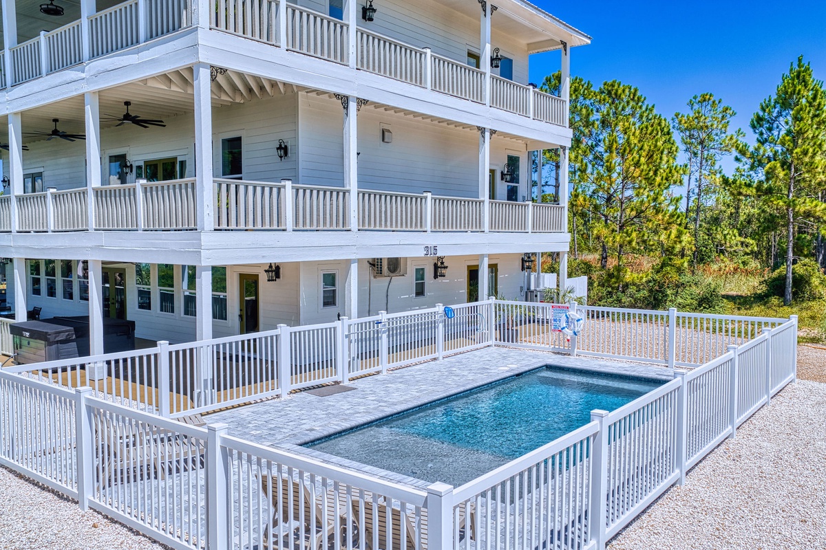 Spacious three-story coastal retreat featuring multiple balconies, a private pool with deck, and natural pine surroundings—perfect for your family beach getaway.