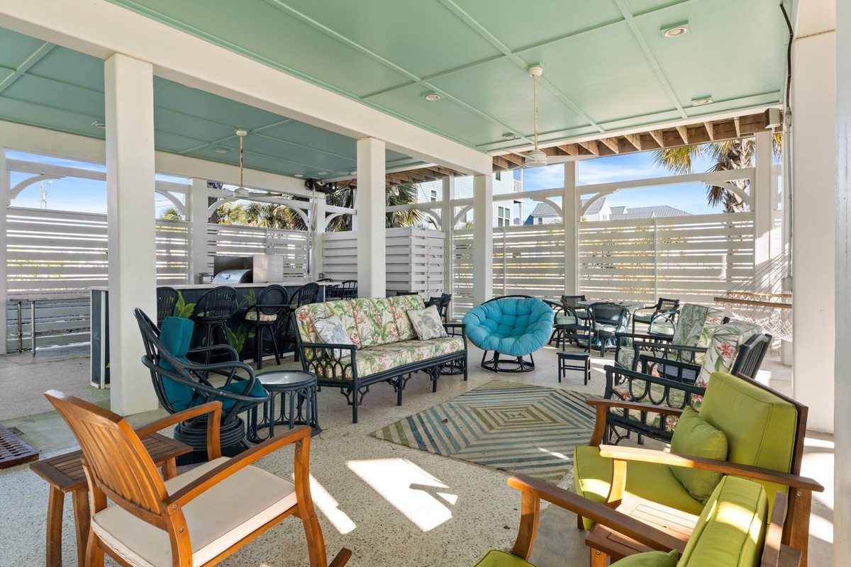 Relax on this vibrant covered patio where colorful seating and tropical breezes create your perfect outdoor retreat.