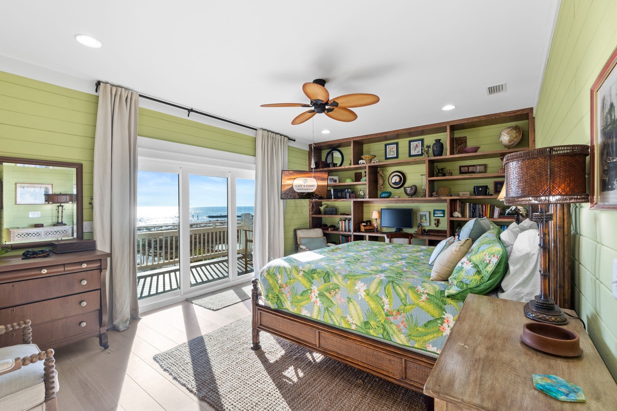 Wake up to stunning ocean views from your tropical-themed bedroom with custom built-in shelving and balcony access for morning coffee.