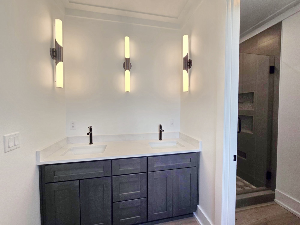Refresh in your elegant dual-sink bathroom with striking modern fixtures and designer lighting that creates the perfect ambiance for your morning routine.