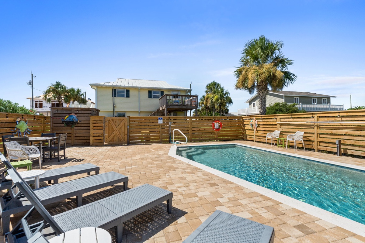 The sparkling pool is framed by warm paver stones and surrounded by comfy loungers—your ideal spot to soak up the Florida sun, cool off with a swim, or enjoy evening cocktails under swaying palms.