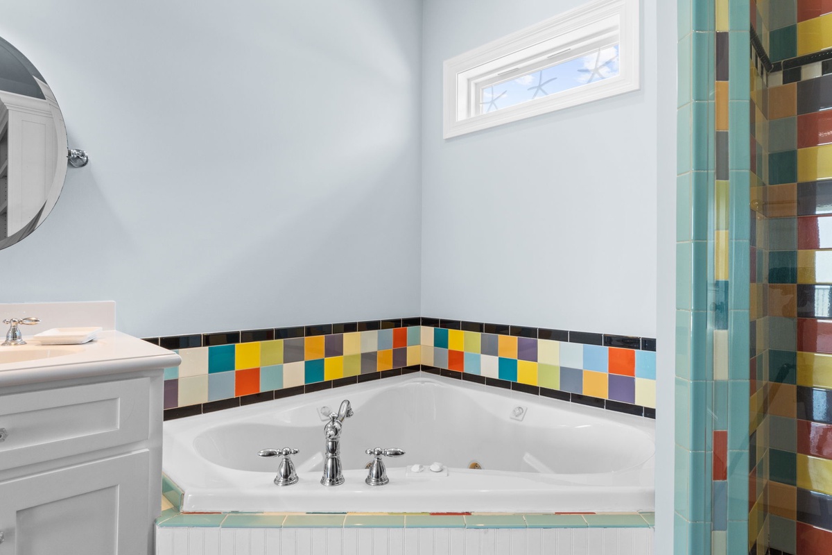 Soak away your cares in this spacious soaking tub, surrounded by cheerful multicolor tile that brings energy and whimsy to your bath time.