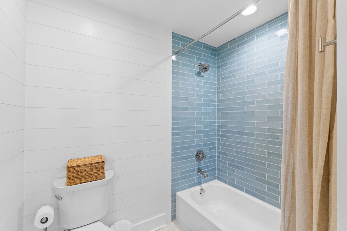 Relax in your spa-like bathroom featuring a pristine tub surrounded by calming blue subway tiles and modern fixtures.