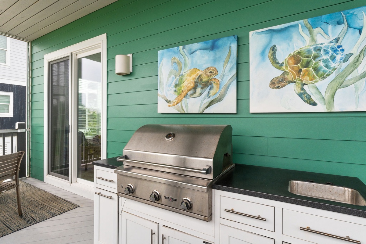 A stainless-steel grill and sink stand ready on your private outdoor balcony, perfect for grilling fresh catches while sea turtle artwork sets a coastal vibe.