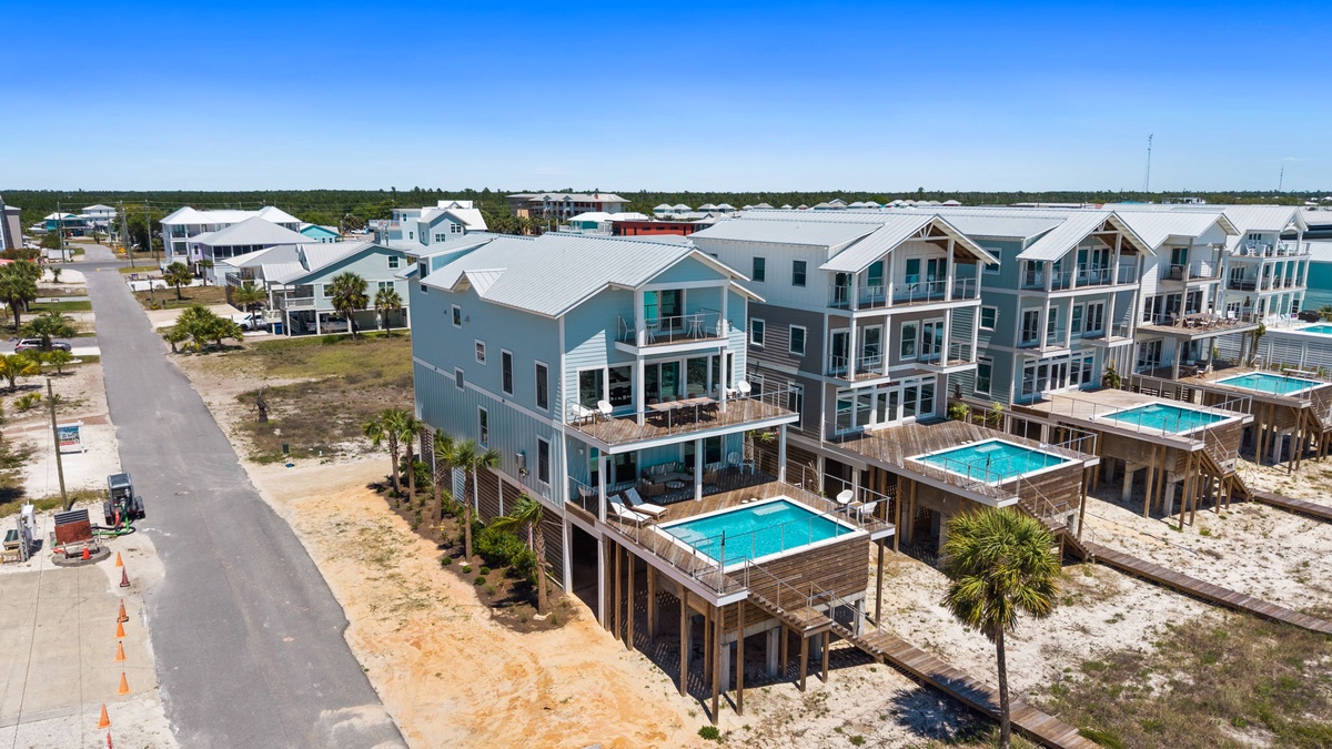 Aerial view of a coastal vacation rental community featuring modern beach houses with private pools, elevated decks, and easy access to waterfront living.