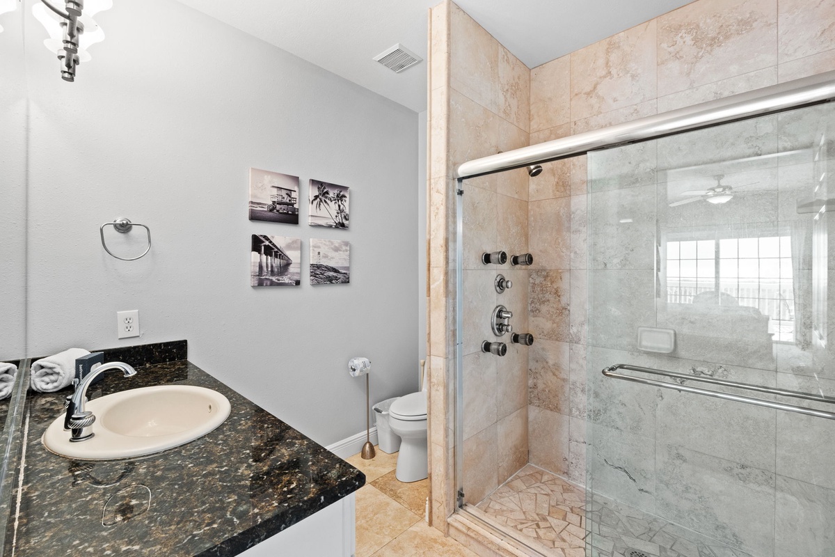 Indulge in your private spa-like retreat with elegant marble shower, granite counters, and coastal artwork creating the perfect ambiance.
