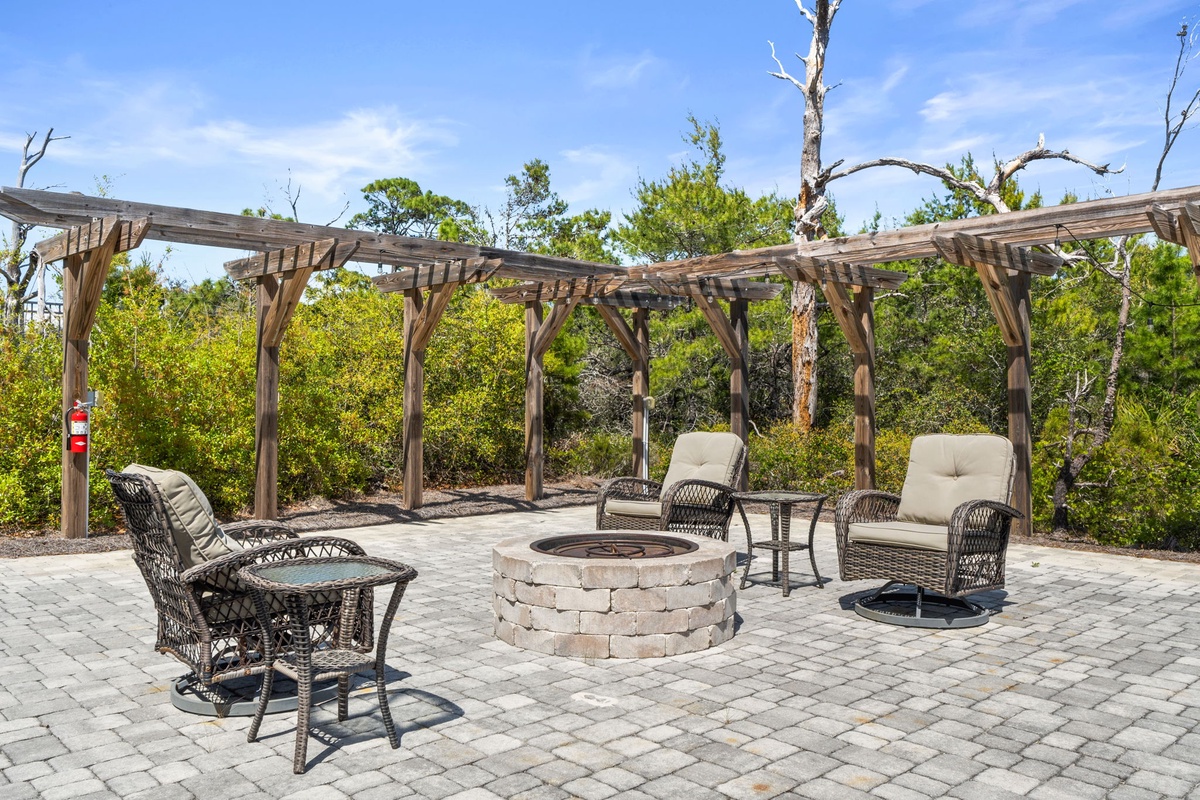 Gather around the fire pit on this beautiful paver patio, where comfortable wicker chairs await your evening conversations under the rustic pergola.