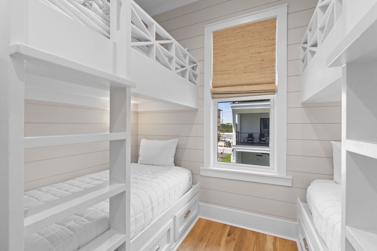 Coastal bunk room with crisp white shiplap and natural light—your perfect spot for rest after beach adventures. Built-in beds offer cozy comfort for family or friends.
