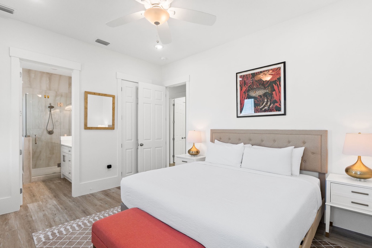 Sink into crisp white linens in your elegant bedroom, complete with an ensuite bathroom and ceiling fan for perfect comfort.