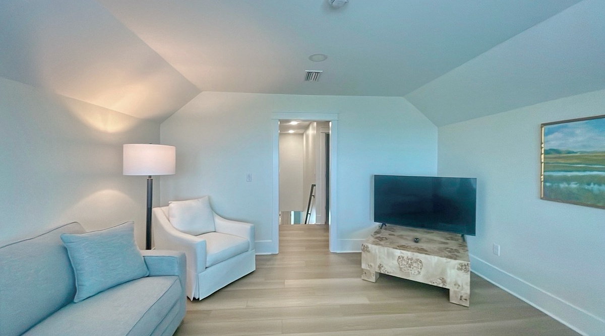 Your private upstairs retreat features vaulted ceilings, serene coastal colors, and a cozy lounge perfect for unwinding with your favorite shows after a day of exploring.