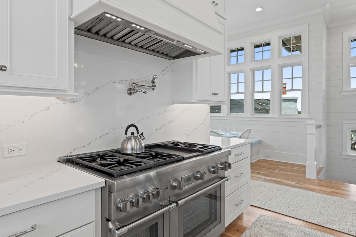 Your fully equipped kitchen features a professional-grade gas range, elegant marble backsplash, and custom white cabinetry—everything you need to prepare delicious meals during your stay.