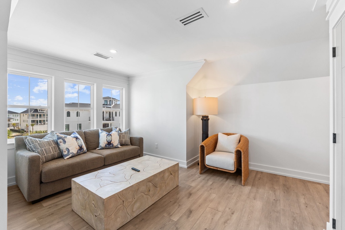 Sink into your stylish living room with modern furnishings, where natural light floods through large windows as you relax on the plush sofa.