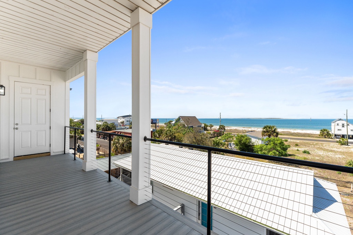 Elevated coastal property balcony with panoramic ocean views and surrounding beach community.