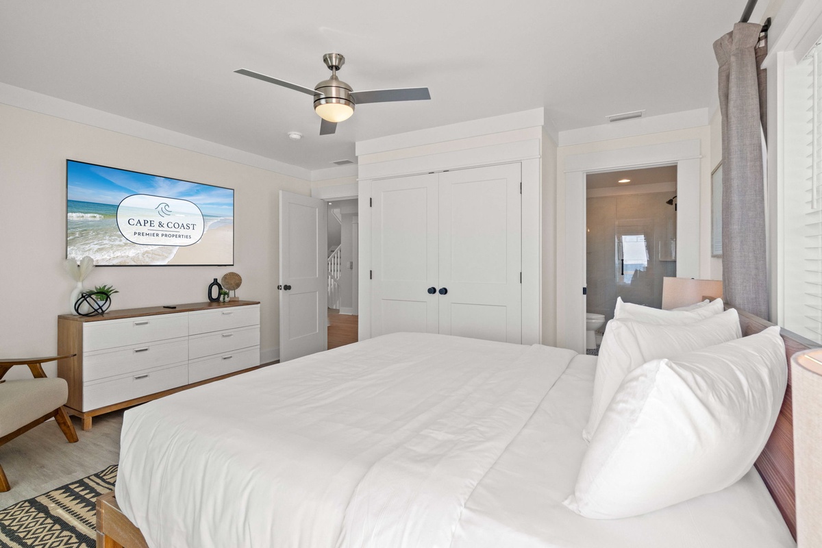 Sink into crisp white linens in your serene master bedroom, complete with modern entertainment and stylish coastal touches for ultimate relaxation.