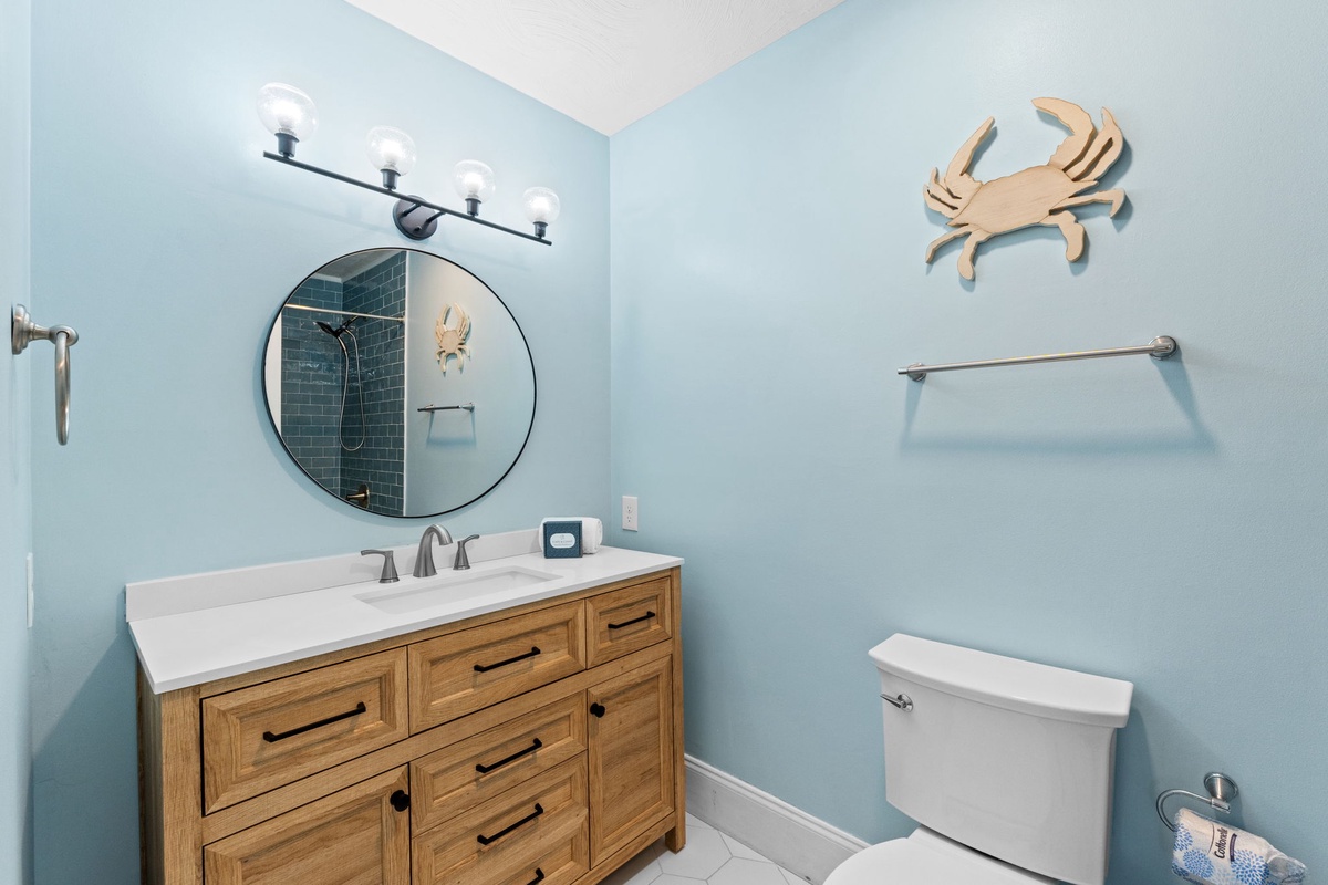 Your coastal-themed bathroom features charming crab decor and warm wood vanity, creating a relaxing seaside retreat.