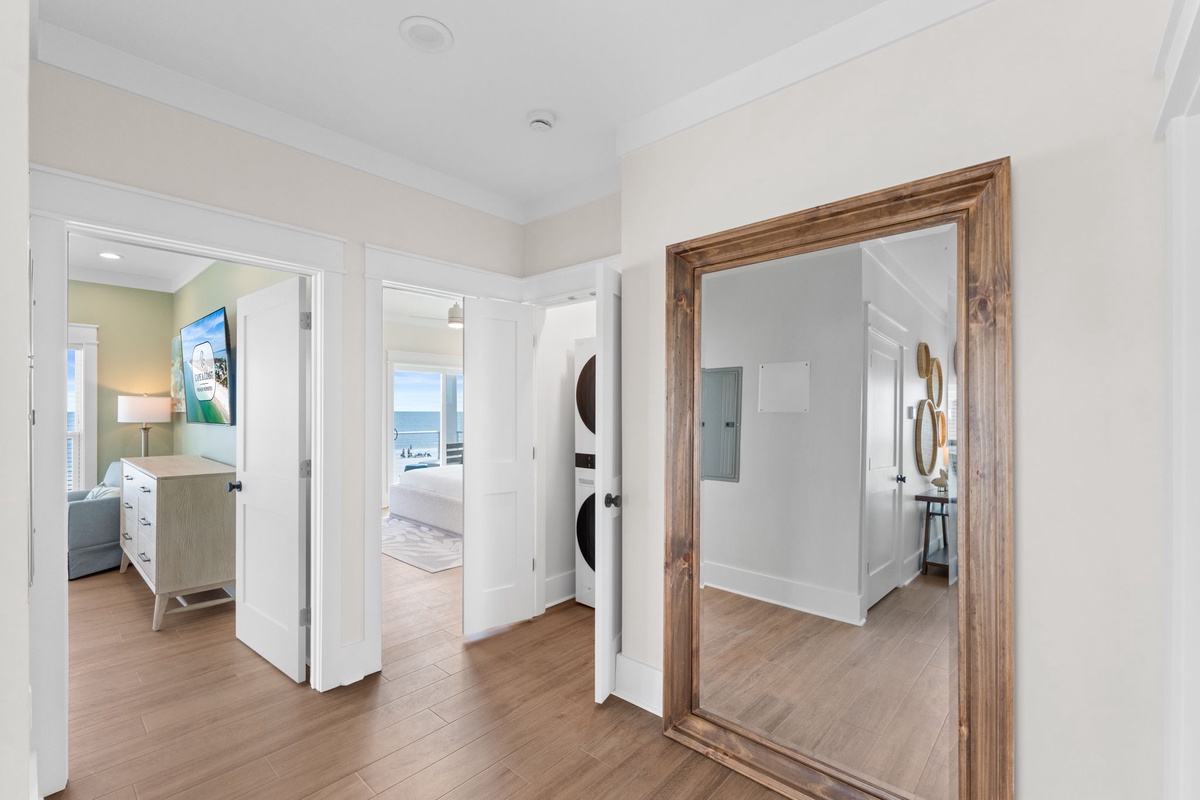 Step into your coastal retreat through this welcoming hallway, where warm wood tones meet ocean breezes. Glimpse your cozy bedroom and spa-like bathroom just beyond, all designed for your ultimate relaxation.